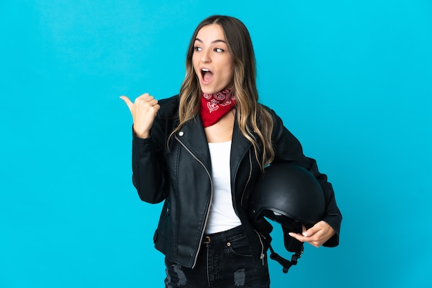 Femme roumaine tenant un casque de moto isolé sur fond bleu dans l'intention de réaliser la solution tout en soulevant un doigt