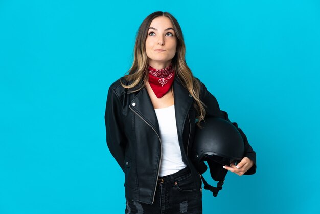 Femme roumaine tenant un casque de moto isolé sur mur bleu et levant