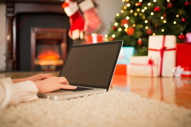 Femme rousse allongée sur le sol en utilisant un ordinateur portable à Noël