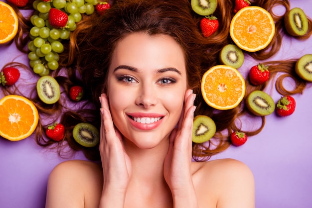 Femme rousse artistique posant avec des fruits dans ses cheveux