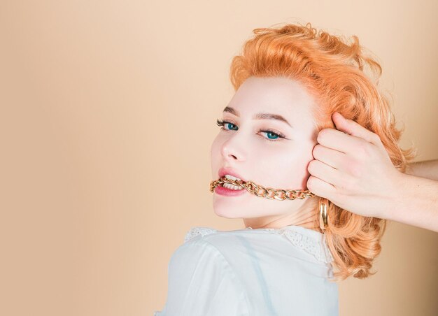 Femme rousse close up portrait avec chaîne en or dans la bouche