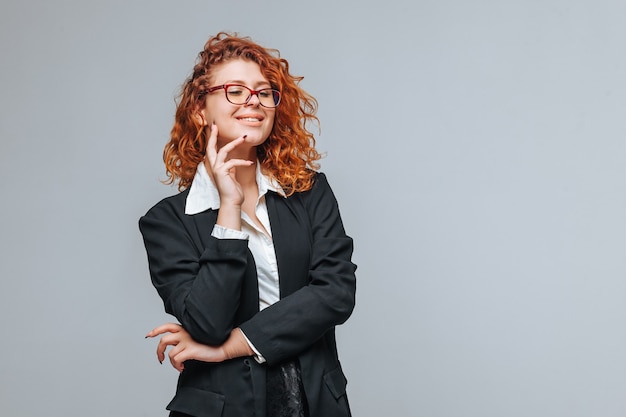 Femme rousse dans une veste noire et des lunettes souriant