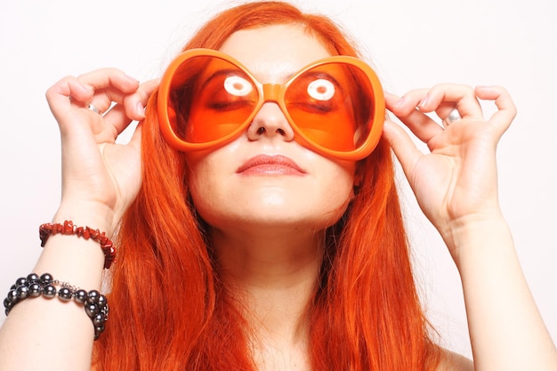 Femme rousse drôle dans de grands verres orange