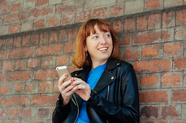 Femme rousse, envoi de message avec smartphone.