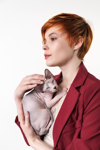 Femme rousse hipster serrant doucement contre sa poitrine Sphynx Hairless Cat Beautiful woman looking away