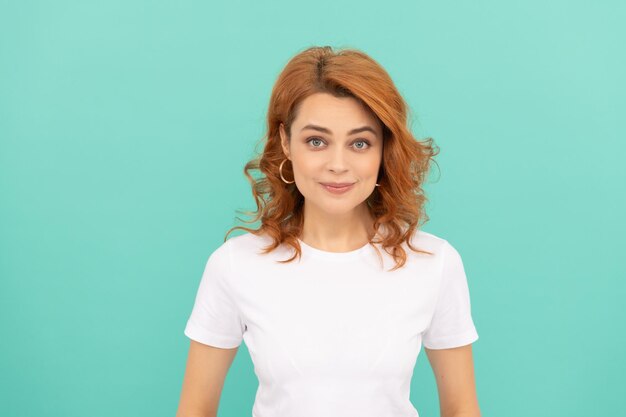 Femme rousse joyeuse aux cheveux bouclés sur fond bleu