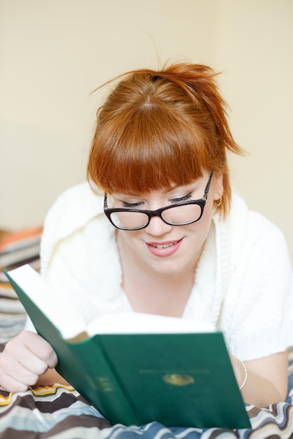 Femme rousse avec un livre sur le lit