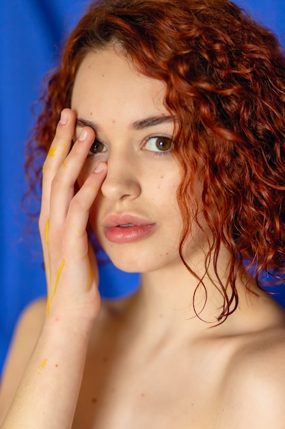 Femme rousse avec les mains peintes en jaune