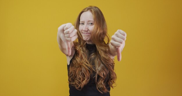 femme rousse malheureuse donnant un geste vers le bas regardant avec une expression négative et une désapprobation