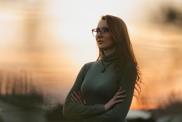 Une femme rousse pose dans le fond du ciel nuageux du soir