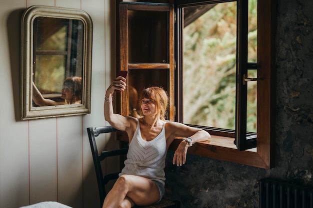 Photo femme rousse prenant un selfie dans une fenêtre