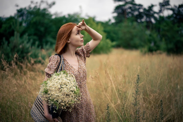 Femme rousse de quarante ans avec un grand bouquet de fleurs sauvages en été dans la nature