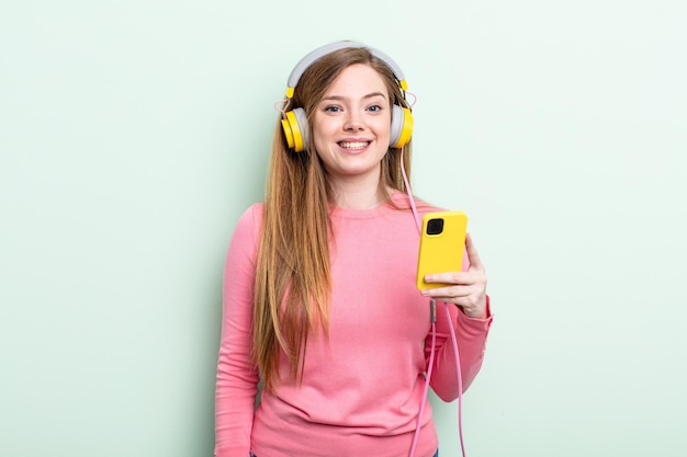 Femme rousse à la recherche d'écouteurs heureux et agréablement surpris et concept de smartphone