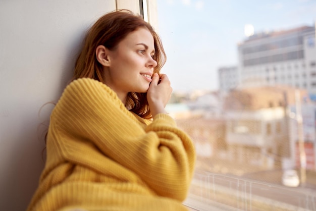 La femme rousse se trouve sur le style de vie du rebord de la fenêtre