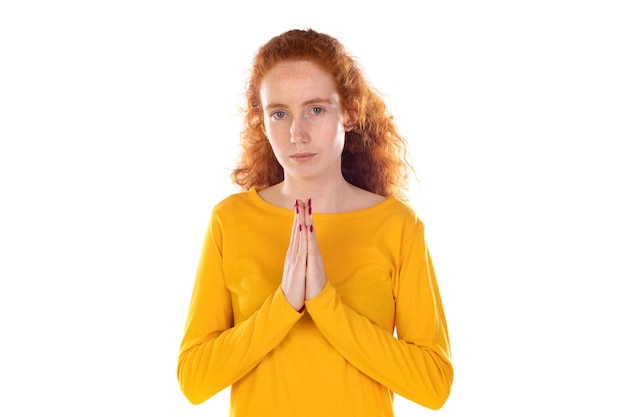Une femme rousse sincère tient les mains ensemble en priant la pose
