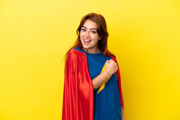 Femme rousse de super héros isolée sur fond jaune célébrant une victoire