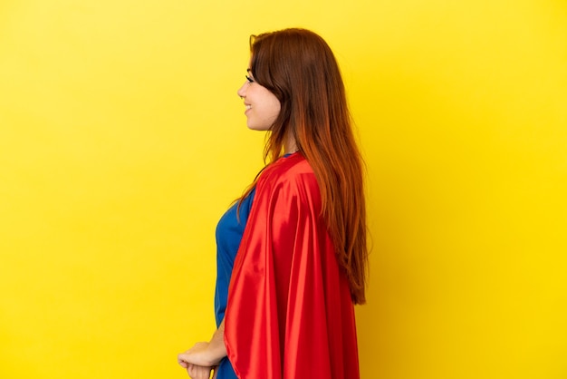 Femme rousse super héros isolée sur fond jaune en position latérale