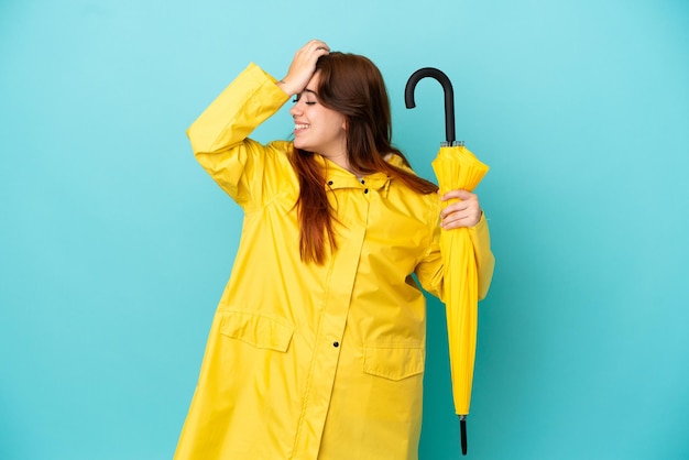 Une femme rousse tenant un parapluie isolé sur fond bleu a réalisé quelque chose et envisage la solution