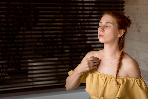 Femme rousse utilisant un masseur en bois pour un auto-massage du cou à la maison