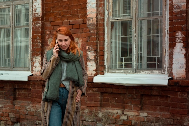 Femme rousse utilisant un téléphone pour appeler à l'extérieur de la ville