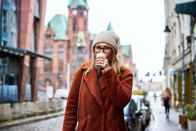 Femme à la rue de la ville avec une tasse de café