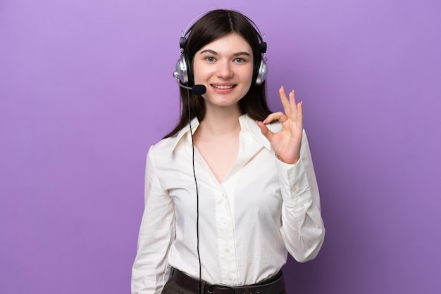 Femme russe de télévendeur travaillant avec un casque isolé sur fond violet montrant un signe ok avec les doigts