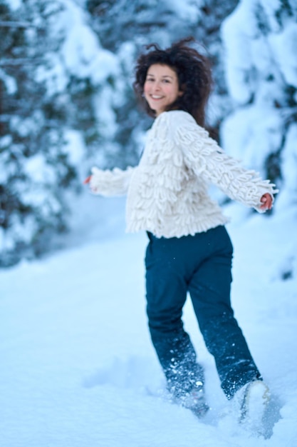 La femme s'amusant à marcher dans la forêt d'hiver couverte de neige