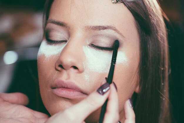 une femme s'applique du maquillage avec un pinceau