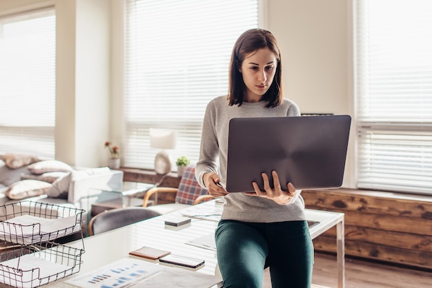 Photo la femme s'assied sur le bureau avec l'ordinateur portable à disposition