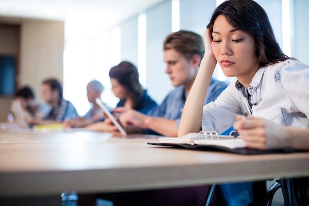 Femme s'ennuie assise dans la salle de réunion avec ses collègues