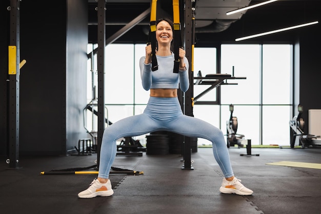 Femme s'entraînant avec des sangles trx fitness dans la salle de sport