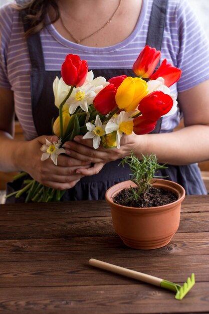 Photo une femme s'occupe des fleurs coupées et fait des bouquets tulipes rouges et jaunes jonquilles fleurs fleuristes publicité