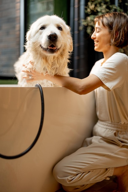 La femme s'occupe de son chien mignon tout en se lavant dans la baignoire