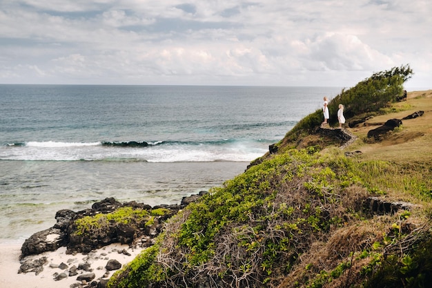 Une femme avec sa fille regarde au loin la plage de GrisGris sur l'île Maurice La famille regarde la belle nature de l'île Maurice et de l'océan Indien