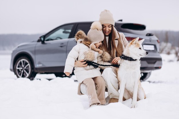 Photo une femme avec sa fille et son chien se promènent dans un parc enneigé près de leur voiture