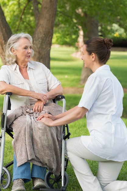 Femme avec sa mère assise dans une chaise roulante au parc