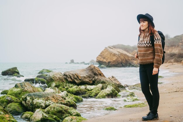 Femme avec un sac à dos sur la côte sur fond de rochers contre belle mer