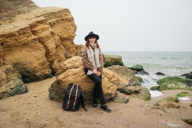 Femme avec un sac à dos sur la côte sur fond de rochers contre belle mer