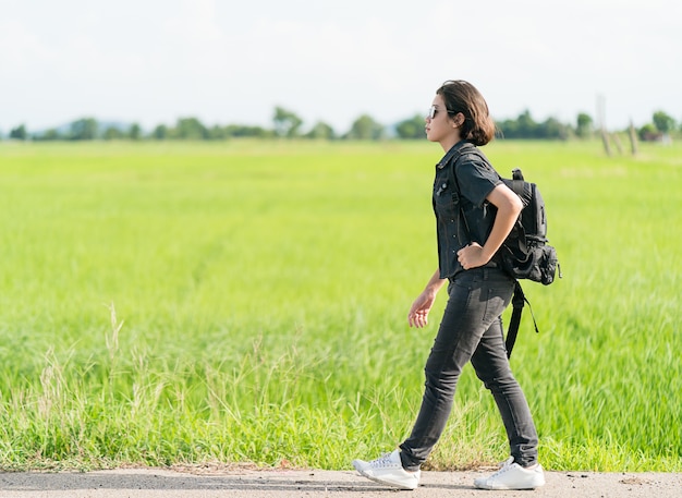 Femme avec sac à dos faisant de l&#39;auto-stop le long d&#39;une route