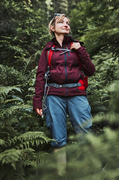 Photo femme avec un sac à dos en randonnée dans la forêt passant activement ses vacances d'été près de la nature