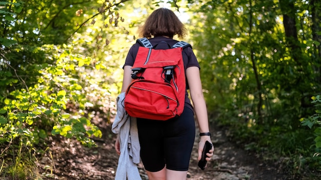 Femme avec sac à dos de randonnée sur un sentier dans une forêt