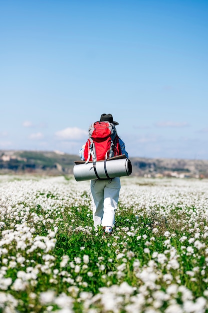 Photo femme avec sac à dos rouge dans un champ fleuri