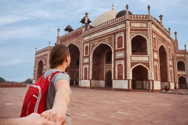 Femme avec sac à dos rouge tenant l'homme à la main allant à la tombe de Humayun39s à Delhi Inde