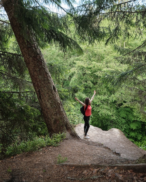 Une femme avec un sac à dos se tient au bord d'une falaise