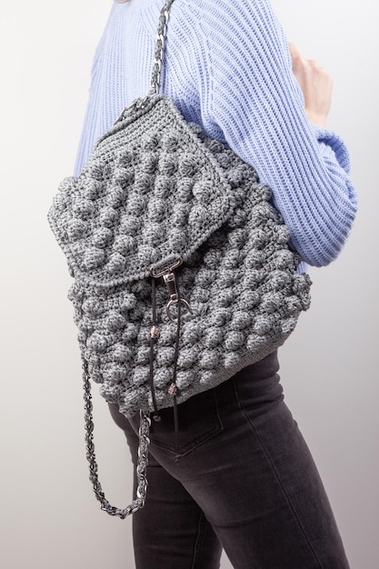 Femme avec sac à dos tricoté sur fond gris