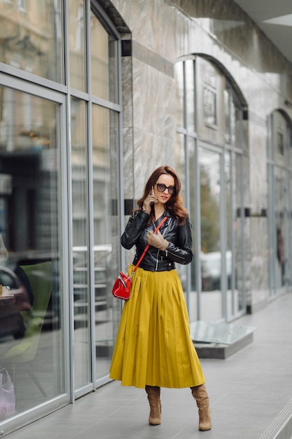 Femme avec sac à main rouge marchant tout en parlant au téléphone près d'un immeuble commercial