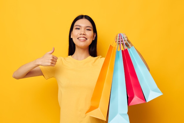 Femme avec des sacs dans ses mains posant sur fond jaune