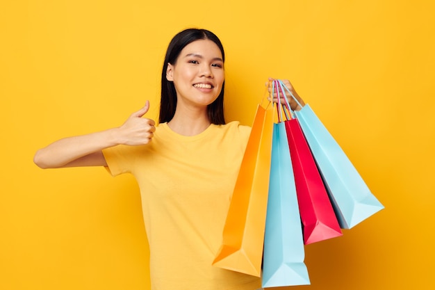 Femme avec des sacs dans ses mains posant sur fond jaune