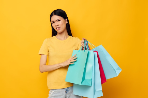 Femme avec des sacs dans ses mains posant sur fond jaune