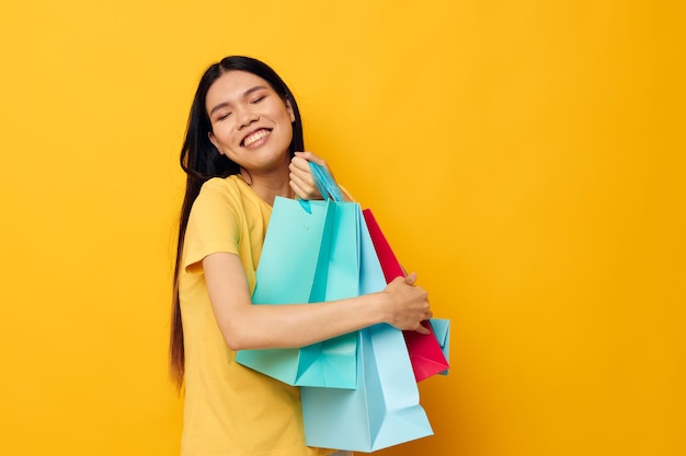 Femme avec des sacs dans ses mains posant sur fond jaune